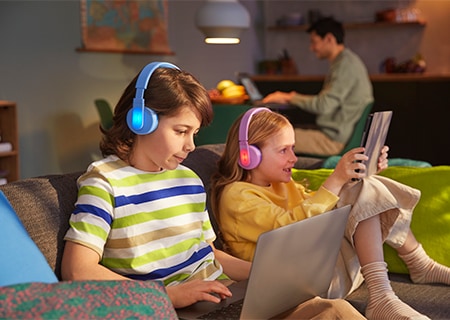 Деца, които използват своите слушалки с наушници Philips с функция на цветни светещи панели