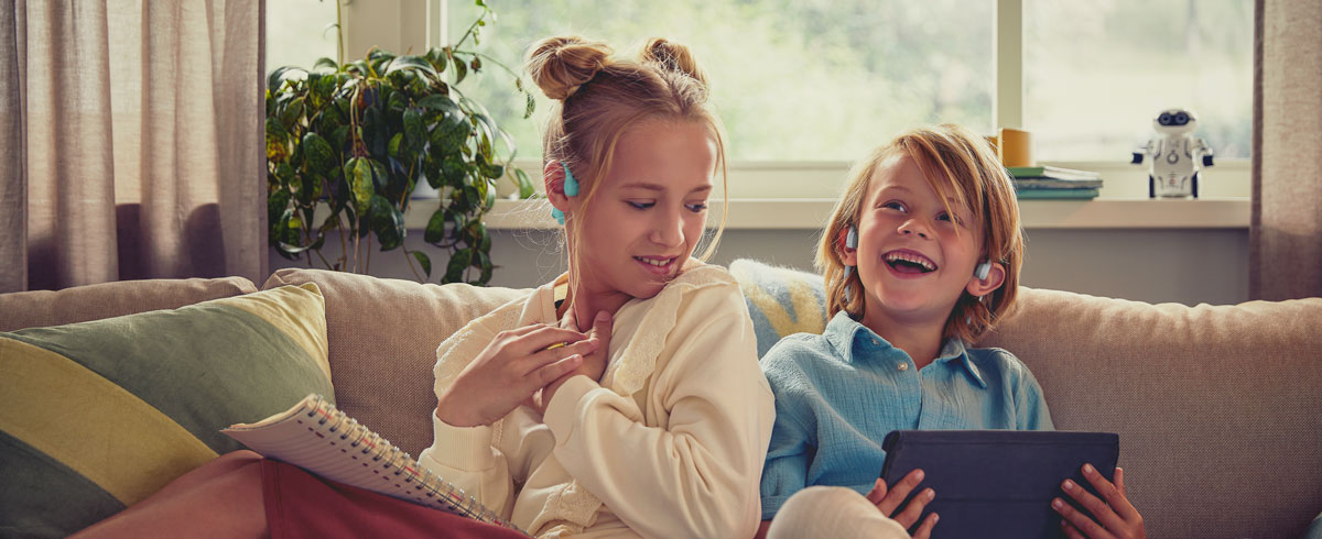 Деца, които се наслаждават на видеоклип, използвайки детски слушалки Philips за открито ухо