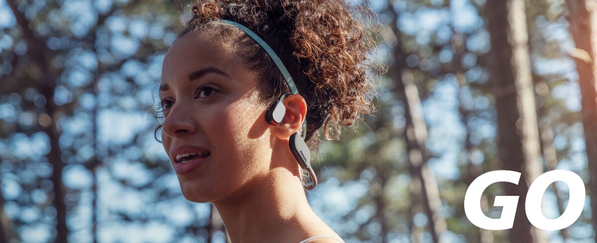 Снимка в близък план на жена, носеща спортни слушалки с костна проводимост