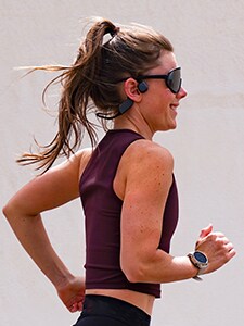 Бягаща жена със слушалки с костна проводимост