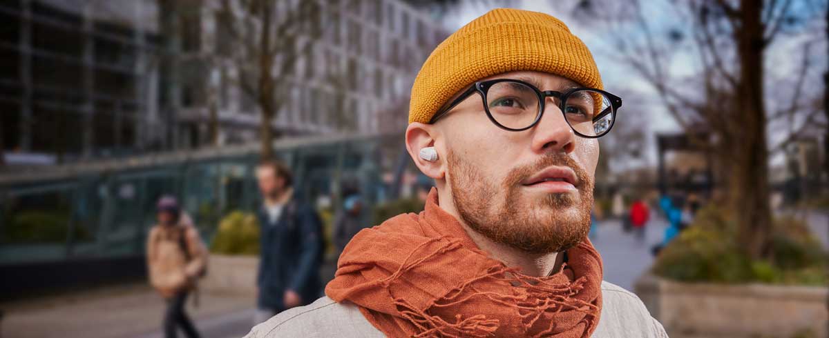 Снимка в едър план на мъж, носещ истински безжични слушалки