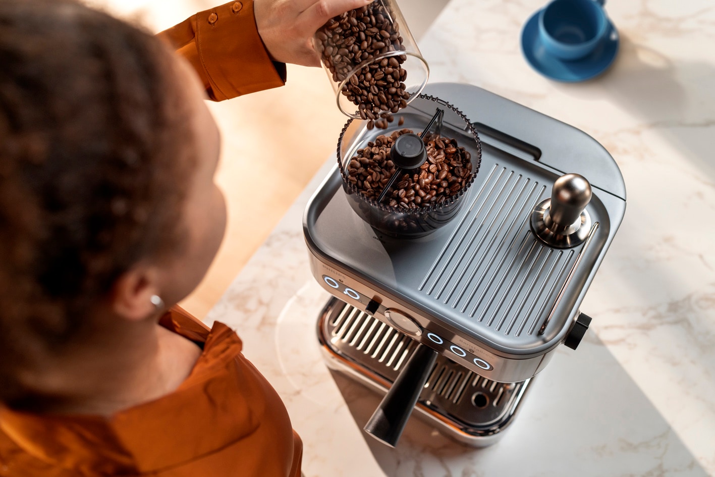 Млада дама изсипва кафени зърна в контейнера за кафе на зърна за Philips Barista Brew